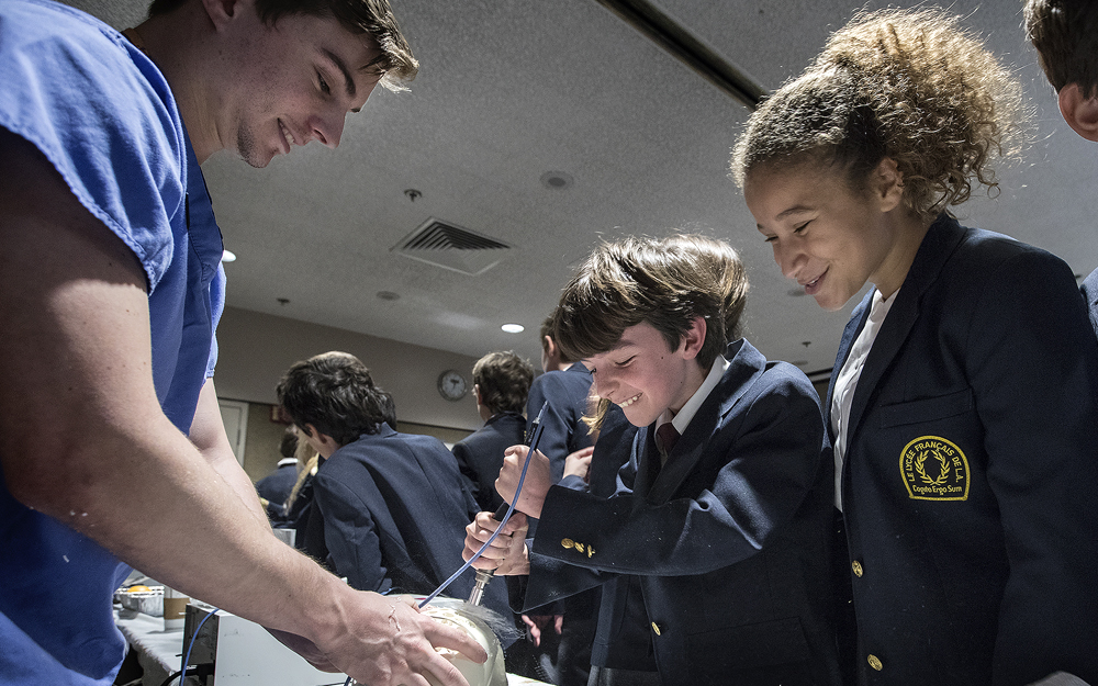 A doctor with a couple of teens holding surgery equipment.