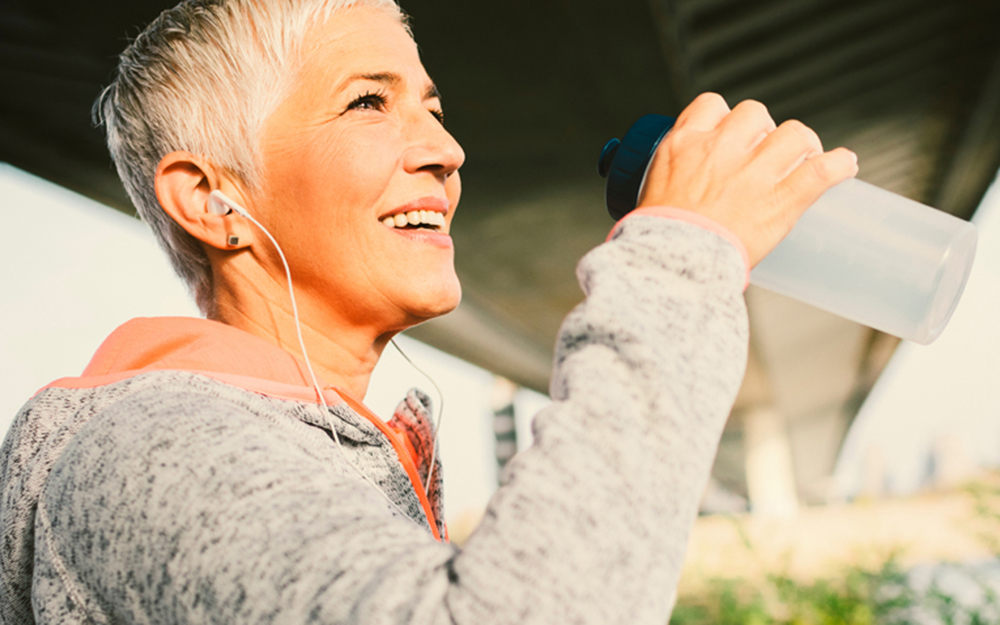 Woman with headphones on drinking water.
