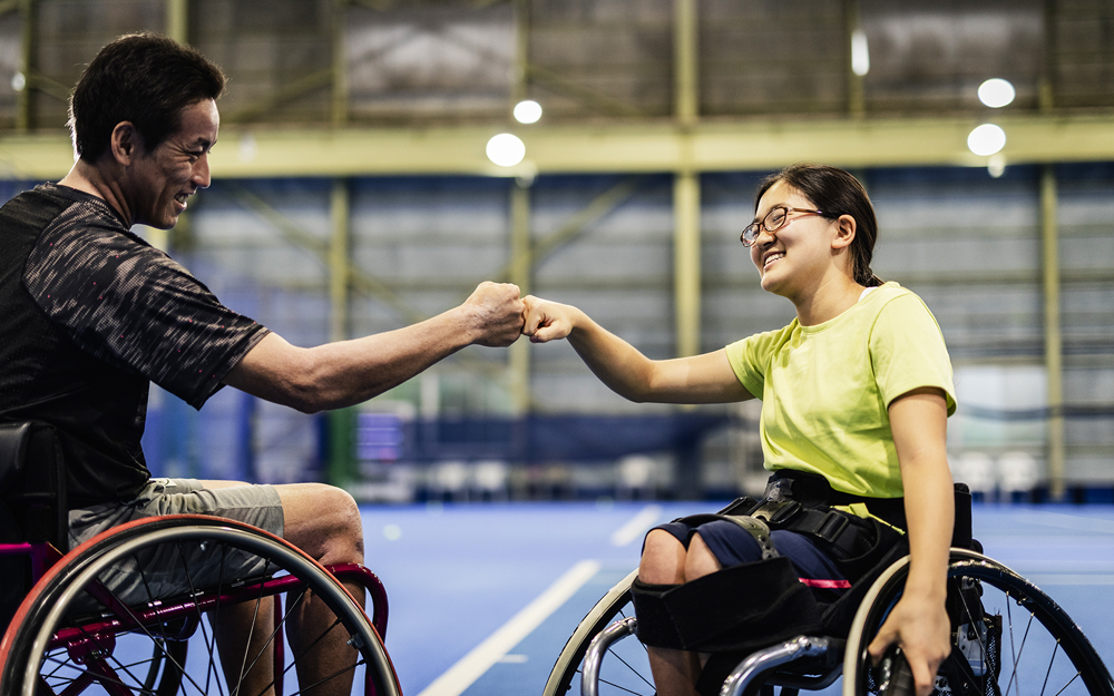 People in wheelchairs giving each other fist bumps.