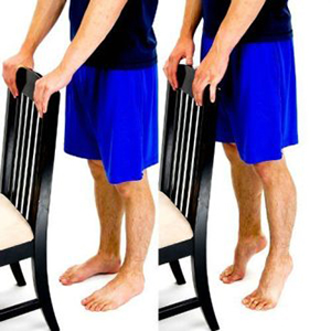 Man holding a chair doing standing heel raises.
