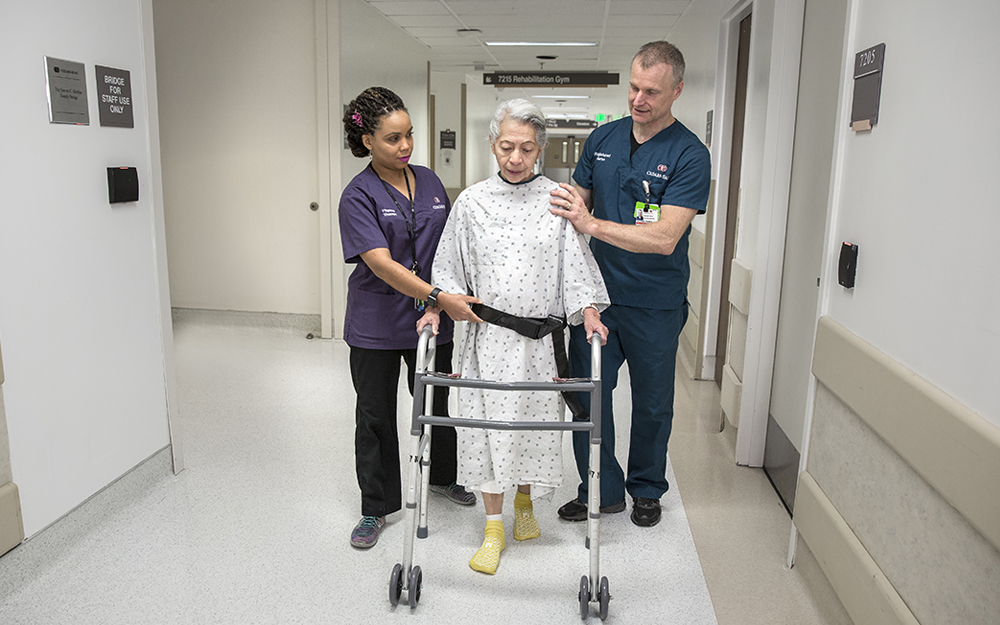 Dennis Harris walking with the assistance with two Cedars-Sinai nurses.