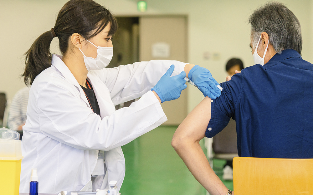 Woman doctor giving a man a Covid-19 vaccine shot.