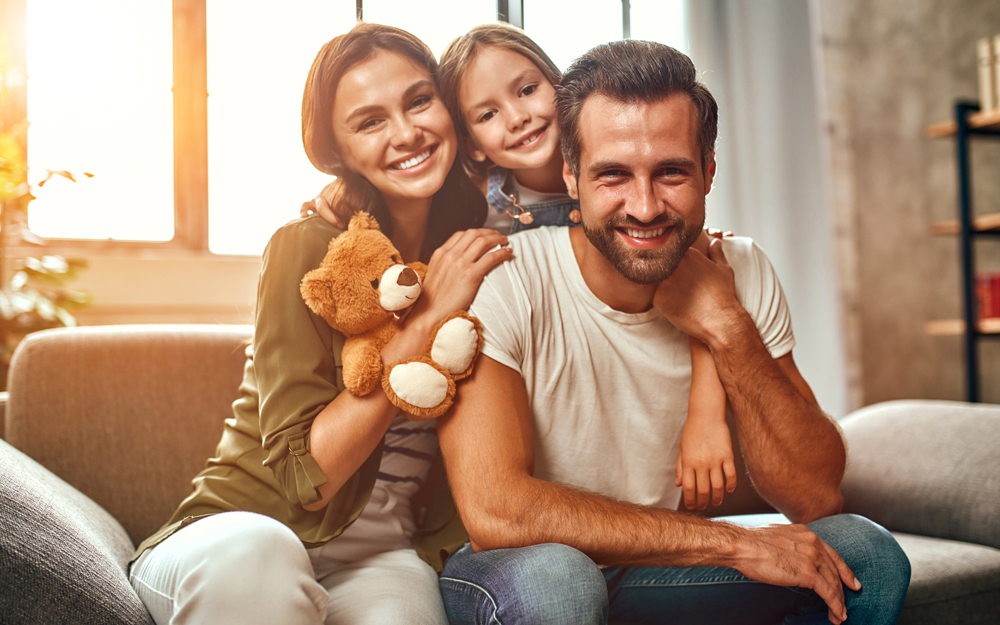 A man considering a vasectomy sitting with his wife and child at home.