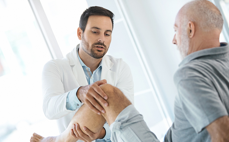 Male doctor examining male patient's knee